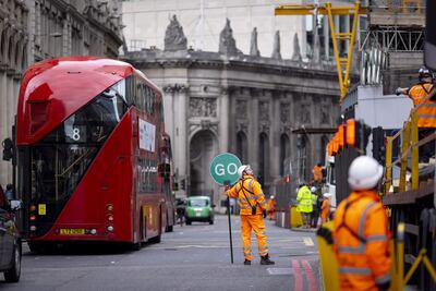 Un trabajador de la construcción dirige el tráfico en el centro de Londres, Reino Unido, mientras sus colegas realizan operaciones.