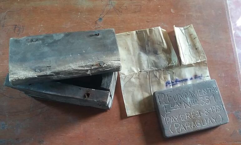 La caja de madera con la placa de piedra y la hoja de papel encontrados en su interior.