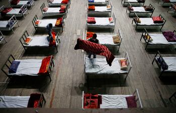 Un hombre trabaja durante las labores de adaptación de un estadio deportivo en un centro de emergencias para atender pacientes afectados por la covid-19 en Srinagar, la capital de verano de la Cachemira India.