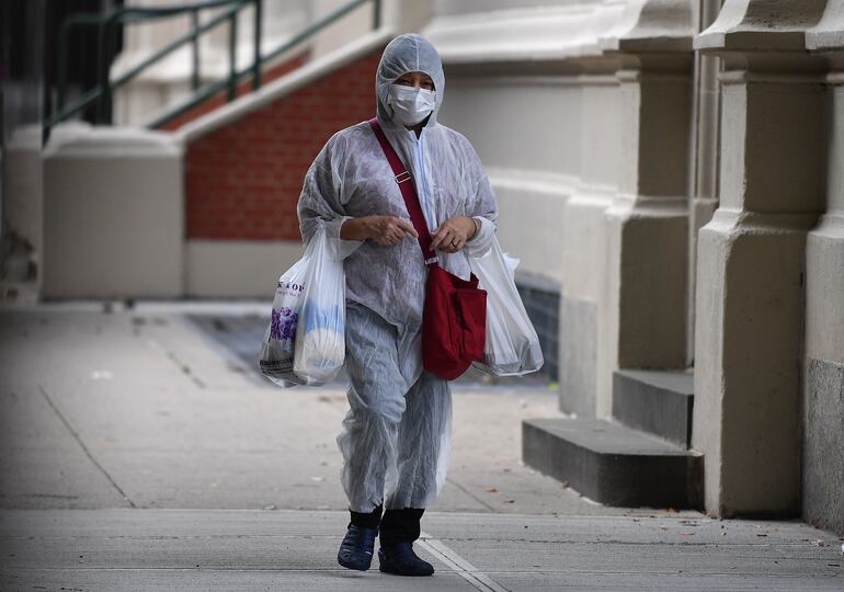 Una persona vestida con un traje de protección camina con bolsas de compras  en Brooklyn, Nueva York.