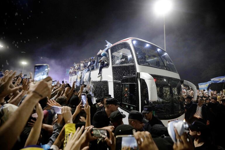 Los jugadores de la selección de Argentina a bordo del bus descapotable durante el recorrido hasta el predio de Ezeiza en compañía de miles y miles de argentinos, que recibieron al plantel en el Aeropuerto Internacional de Ezeiza después de la conquista del Mundial Qatar 2022. 