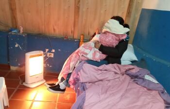 Ya cobijados del frío, la madre y el pequeño comparten el calor de una estufa en el albergue en el que pasarán la noche.
