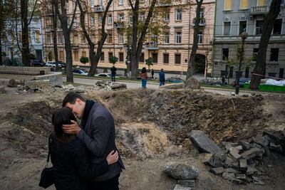 Una pareja junto a un cráter causado por un bombardeo en el centro de Kiev.