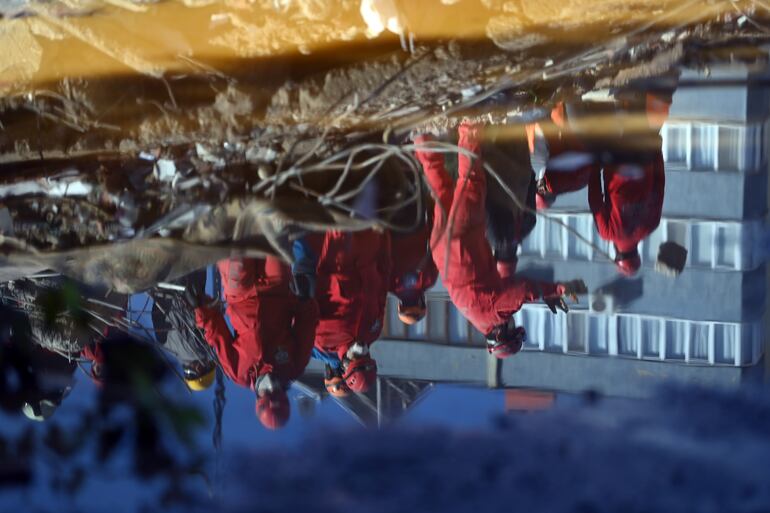 La imagen de un grupo de rescatistas se refleja en un charco frente a un edificio colapsado, en la ciudad de Izmir, Turquía.