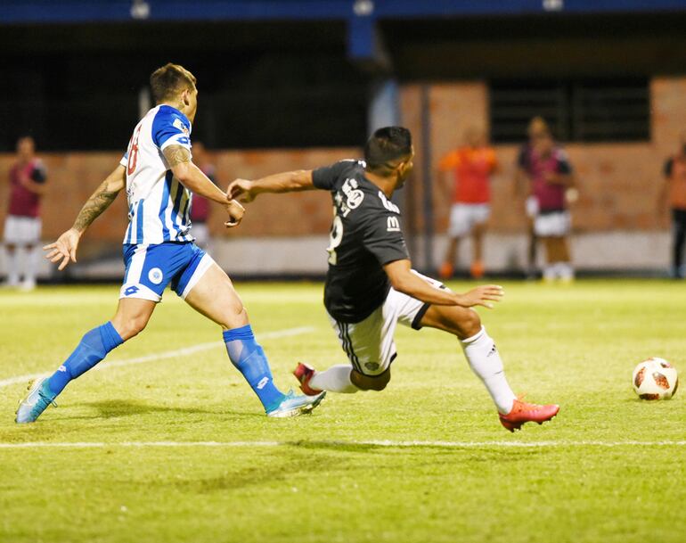 Cayendo al piso Jorge Rojas sacó el remate que se convertirá en el tercer gol de Olimpia, a poco de comenzar el segundo tiempo, anoche en Itauguá. Víctor Ayala queda en su intento de marcar.
