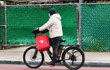 Un repartidor de comida para la aplicación Doordash pedalea su bicicleta eléctrica en Flatbush, Brooklyn, Nueva York.