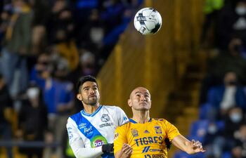 Carlos González (adelante) de Tigres de UANL disputa el balón con Diego de Buen (atrás) de Puebla, durante un partido correspondiente a la jornada 2 del Torneo Clausura 2022 de México.