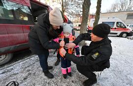 Voluntarios le prueban un chaleco antibalas a una niña en Kharkiv, Ucrania.