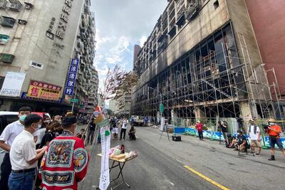 Parientes de los fallecidos en el incendio de la torre en Kaohsiung rezan frente al edificio siniestrado.