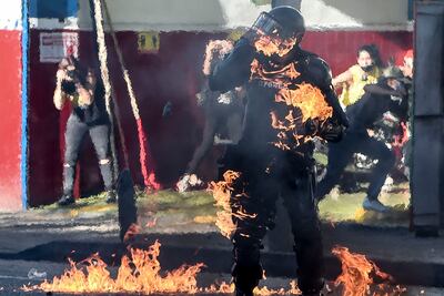Un policía es alcanzado por una bomba molotov durante enfrentamientos de los uniformados con manifestantes que protestan contra la violencia policial, el jueves en Medellín, Colombia.