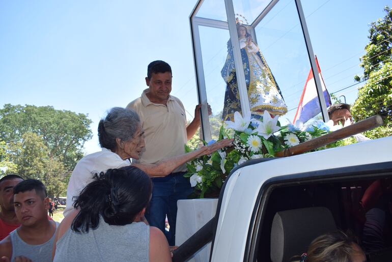 Una mujer de la tercera edad cargada en los brazos de su hija, también dio la bienvenida a la Virgen de  los Milagros que visita a la comunidad  de la compañía Cocué Guasú de Areguá.
