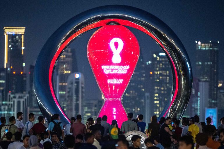 TOPSHOT - People gather in front of the World Cup countdown clock in Doha on November 17, 2022, ahead of the Qatar 2022 World Cup football tournament. (Photo by Philip FONG / AFP)