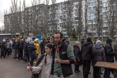 Tom Hughes, voluntario escocés posa con una joven ucraniana mientras forman fila para recibir pizzas en Kherson, al sur de Ucrania.