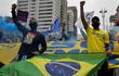 People raise their clenched fists as they demonstrate with a Brazilian flag against Brazilian President Jair Bolsonaro and racism, in Sao Paulo, Brazil, on June 14, 2020, amid the novel coronavirus pandemic. (Photo by NELSON ALMEIDA / AFP)
