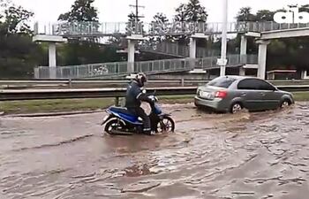 Automóviles y motocicletas tientan su suerte pasando los cúmulos de agua en la Ruta PY03.