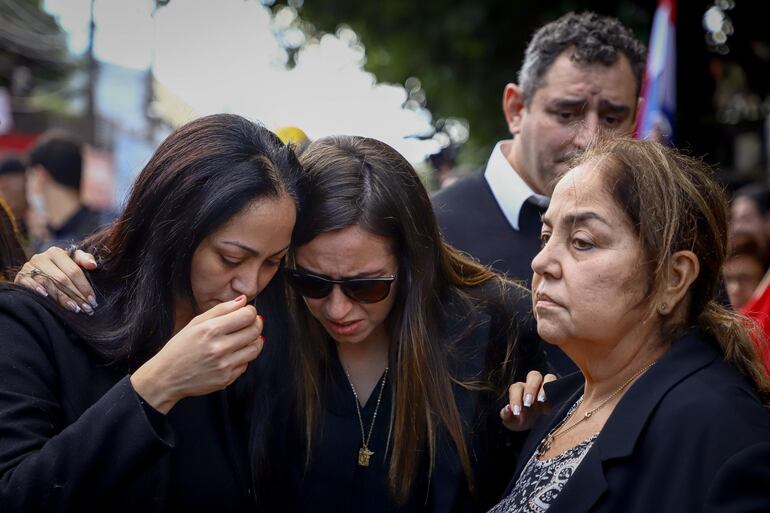 Mónica Pecci, Claudia Aguilera  y Maricel Albertini, hermana, esposa y madre del asesinado fiscal Marcelo Pecci, se lamentan hoy frente a la sede del Club Guaraní en Asunción (Paraguay). 
