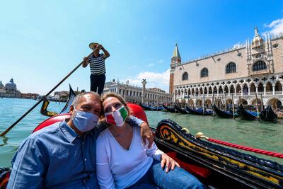 Una pareja con tapabocas disfruta de un paseo en góndola frente al Palacio Ducal, en Venecia.