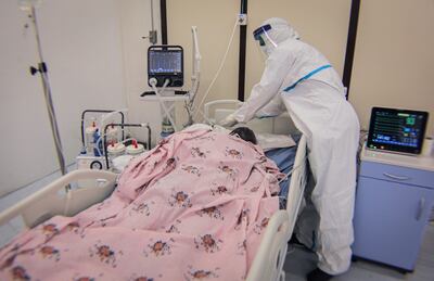 Personal médico vestido con traje de protección atiende a un paciente con coronavirus en la Unidad de Terapia Intensiva.