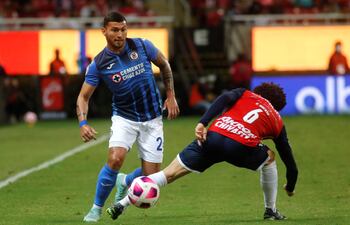 El paraguayo Juan Escobar, del Cruz Azul, intenta controlar el balón ante el mexicano César Huerta, de Chivas Guadalajara, durante el partido que disputaron Estadio Akron, en Guadalajara.