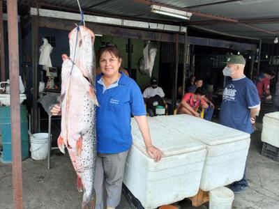 Cecilia Portillo muestra un hermoso ejemplar de surubí que tiene para la venta en su puesto de la ciudad de San Antonio.
