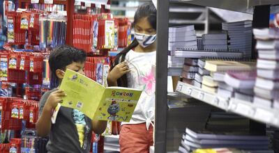 Dos niños observan ilusionados los artículos que desean se les compre este año de la tienda.
