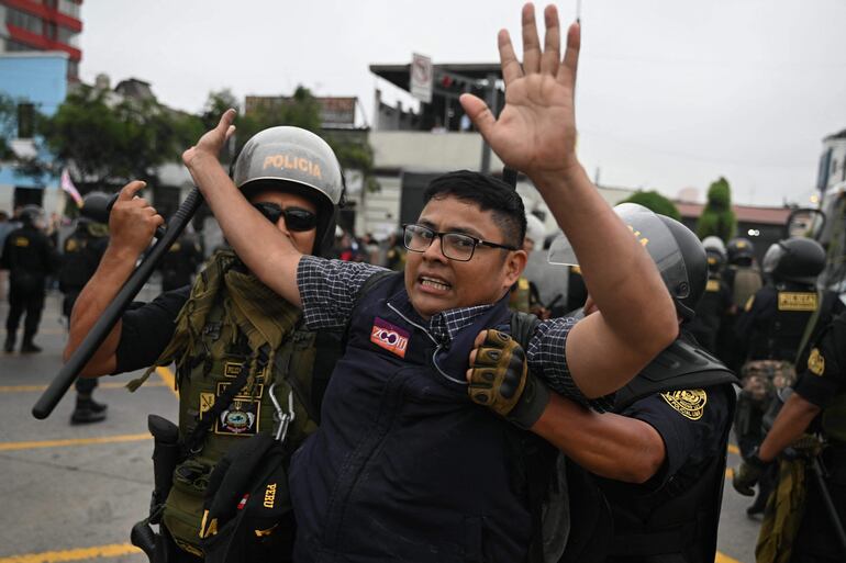 A supporter of Peruvian President Pedro Castillo is carried away by the police in the outskirts of the Lima Prefecture, where Castillo is under detention, in Lima, on December 7, 2022. - Peru's President Pedro Castillo dissolved Congress on December 7, 2022, announced a curfew and said he will form an emergency government that will rule by decree, just hours before the legislature was due to debate a motion of impeachment against him. (Photo by ERNESTO BENAVIDES / AFP)