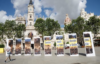 Un transeúnte observa las fotografías de la exposición "Somiar molt i dormir poc" ( soñar mucho y dormir poco) que se ha inaugurado en la Plaza del Ayuntamiento de Valencia en el décimo aniversario del movimiento 15M.