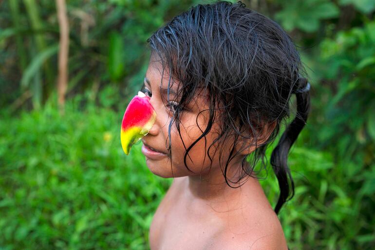 Una niña yuqui con una flor Pico de Loro sobre la nariz, en una de las imágenes que componen el ensayo de Sara Aliaga.