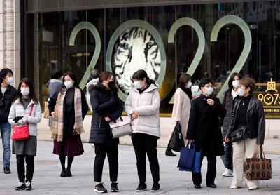 Personas con tapabocas pasan frente a un gran cartel que anuncia el año nuevo, en Tokio, Japón, una de las ciudades de ese país en la que se reanudaron las restricciones para hacer frente a una nueva ola de Covid.