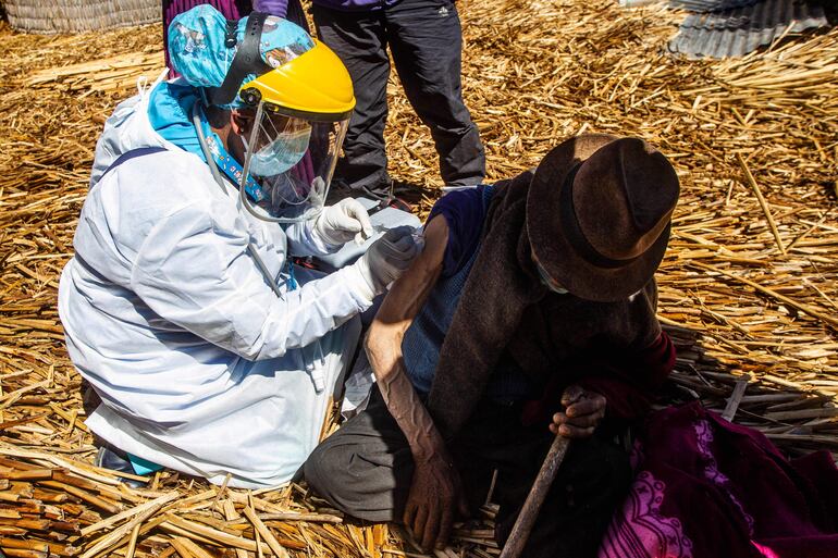 Un trabajador de la salud inocula a un hombre con una dosis de la vacuna Sinopharm en una localidad a orillas del lago Titcaca en Puno, Perú.