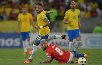 El chileno Arturo Vidal queda en el suelo, mientras el brasileño Neymar se apresta para seguir con la jugada.