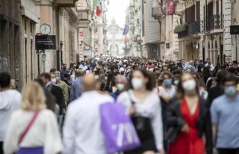 Decenas de personas caminan por una calle de Roma.