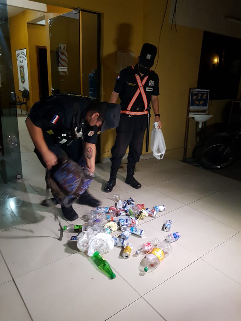 Agentes muestran las bebidas alcohólicas incautadas del bus en que iban los hinchas, que fueron tomadas como evidencia para el arresto.