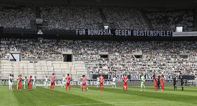 Protagonistas del partido entre Mönchengladbach y Leverkusen en el círculo central. Atrás, los hinchas de cartón.