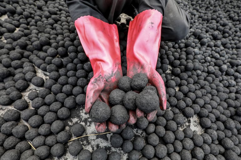 Un trabajador de Kenia arregla briquetas hechas de una mezcla de lodo de desechos humanos triturado y aserrín aglutinado con melaza en un lecho de secado.
