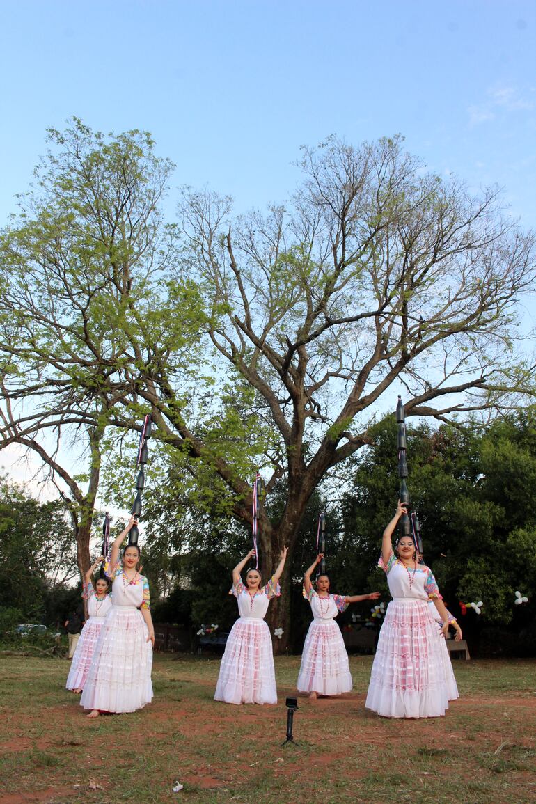 Bailarinas reciben a la comitiva de los Colosos en un barrio de Areguá. De fondo, el Timbó que se postula este año.