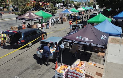 Los voluntarios cargan alimentos gratis en los automóviles para las personas necesitadas en un banco comunitario de distribución de alimentos en el vecindario Crenshaw de Los Ángeles, California.