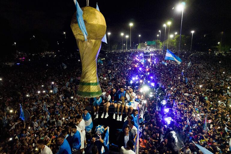 Los jugadores de la selección de Argentina a bordo del bus descapotable durante el recorrido hasta el predio de Ezeiza en compañía de miles y miles de argentinos, que recibieron al plantel en el Aeropuerto Internacional de Ezeiza después de la conquista del Mundial Qatar 2022. 
