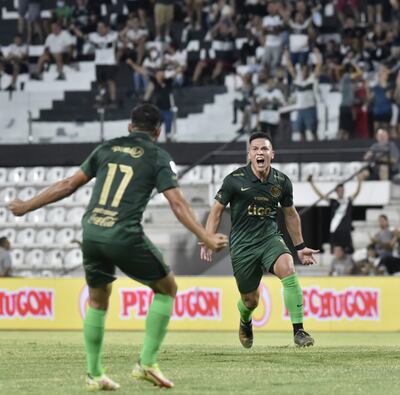 Feliciano “Peta” Brizuela abre los brazos para recibir a Hugo Lorenzo Quintana, autor del primer gol.  Olimpia marcha en onda verde, conforme a su vestimenta estrenada anoche en su estadio.