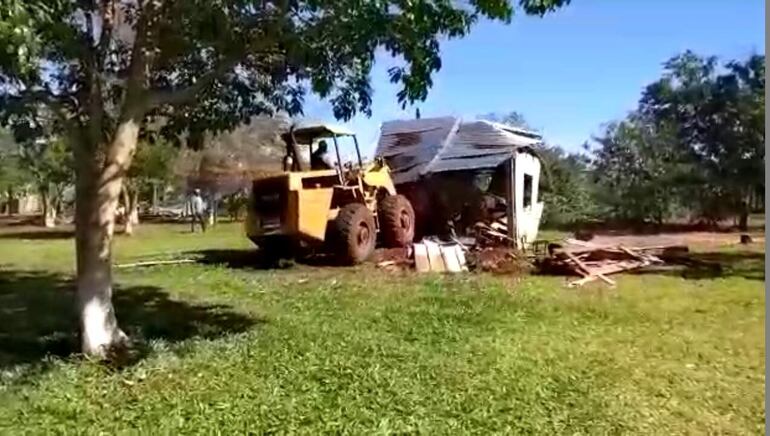 Momento en que un tractor con pala derriba el local educativo de la comunidad.