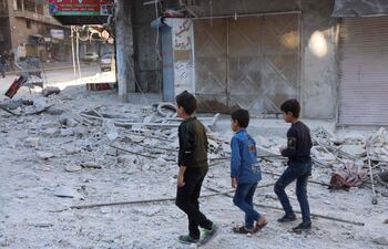 Niños pasan junto a los escombros en el lugar del bombardeo en la ciudad siria de Ariha, en la provincia de Idlib, en el noroeste de Siria.