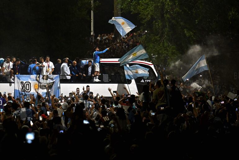 Los jugadores de la selección de Argentina a bordo del bus descapotable durante el recorrido hasta el predio de Ezeiza en compañía de miles y miles de argentinos, que recibieron al plantel en el Aeropuerto Internacional de Ezeiza después de la conquista del Mundial Qatar 2022. 