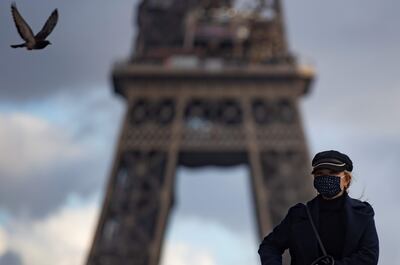 Una parisina con mascarilla pasa frente a la Torre Eiffel en París, Francia.
