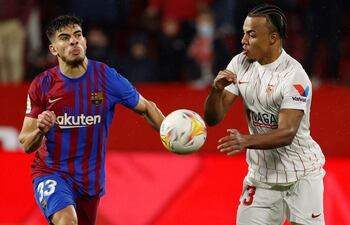 Jules Koundé (d), quien fue expulsado por tirar la pelota a la cara a Jordi Alba, disputa el balón con Abdessamad Ezzalzouli.