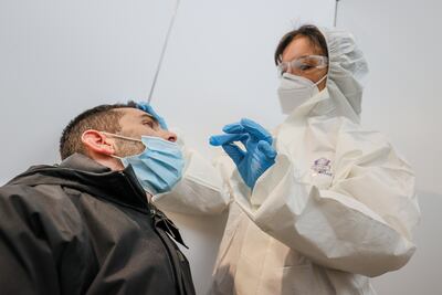 Una trabajadora de la salud toma una muestra de un viajero para una prueba de covid-19 en el aeropuerto Liege, en Bélgica.