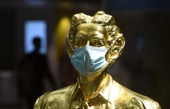 Una estatua dorada que representa al ex rey bávaro Ludwig II está decorada con una máscara facial protectora en una sala terminal del aeropuerto "Franz-Josef-Strauss" en Munich, sur de Alemania.