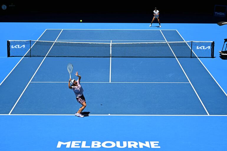 Iga Swiatek de Polonia (abajo a la izquierda) sirve a Madison Keys de EE. UU. (arriba a la derecha) durante una sesión de práctica antes del torneo de tenis del Abierto de Australia en Melbourne el 11 de enero de 2023.