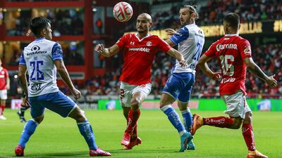 Carlos González tiene en la mira el balón ante la marca de dos jugadores del Puebla.