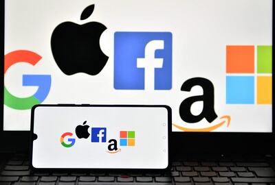 Logos de Google, Apple, Facebook, Amazon y Microsoft en la pantalla de un celular y una laptop.