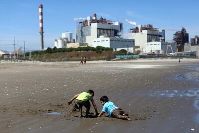 (En esta foto de archivo tomada el 8 de octubre de 2019, niños juegan en la arena de la playa Las Ventanas junto a la planta termoeléctrica AES Gener en Puchuncaví, región de Valparaíso, Chile.